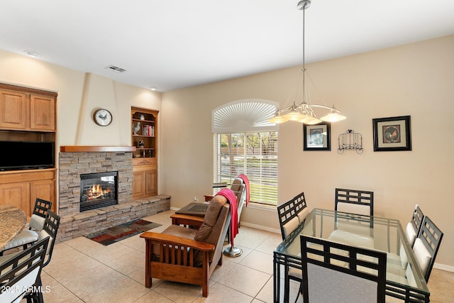 living room featuring light tile patterned flooring, baseboards, visible vents, and a stone fireplace