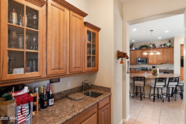 kitchen with brown cabinetry, stainless steel microwave, a sink, and a breakfast bar area