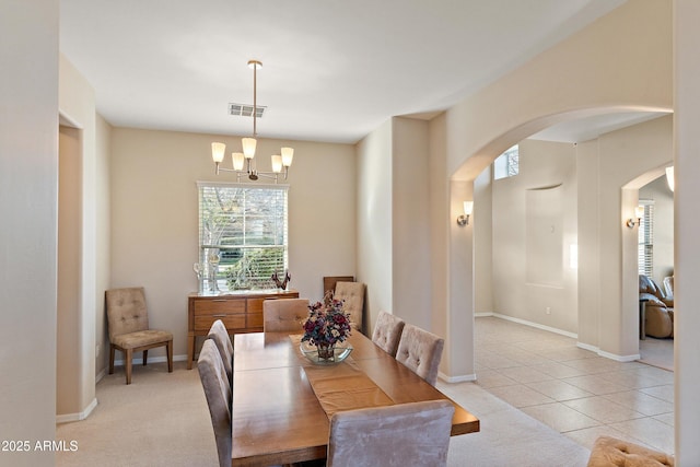 dining space featuring arched walkways, light tile patterned floors, visible vents, an inviting chandelier, and baseboards