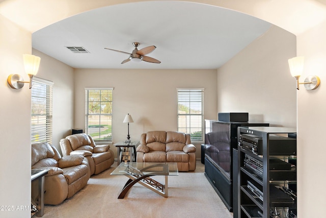 living area featuring a ceiling fan, visible vents, a wealth of natural light, and light colored carpet