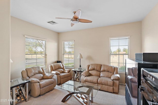 living area with carpet floors, visible vents, and ceiling fan