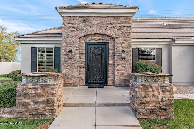 property entrance featuring stone siding, a tiled roof, and stucco siding