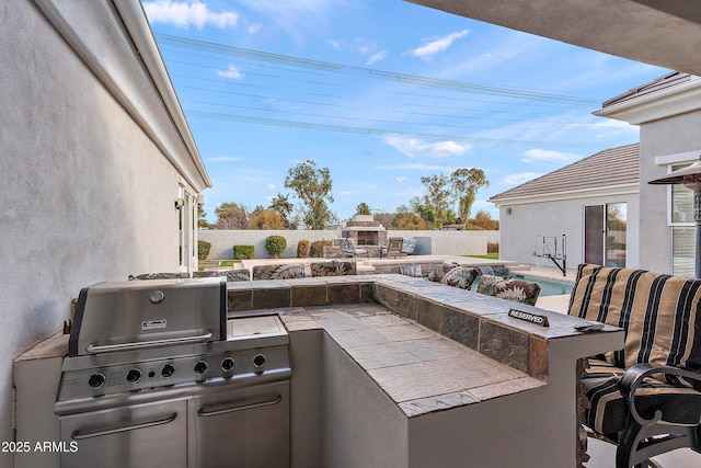 view of patio / terrace with a fenced in pool, grilling area, exterior kitchen, a fenced backyard, and an outdoor fireplace