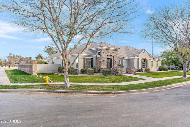 view of front of home with fence, stone siding, a tiled roof, stucco siding, and a front lawn