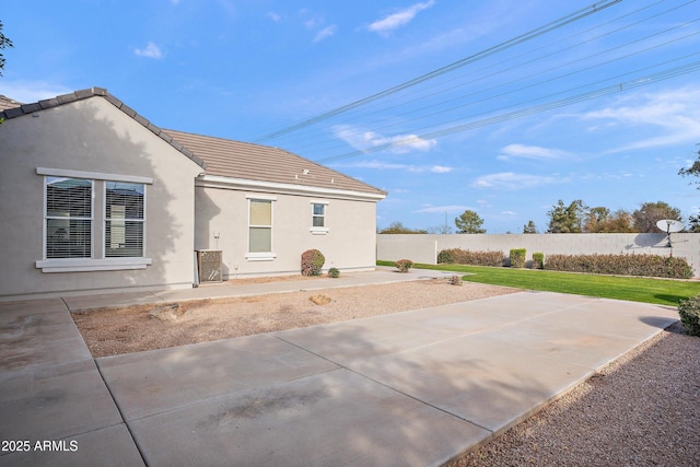 back of property featuring a yard, a patio, stucco siding, fence, and a tiled roof