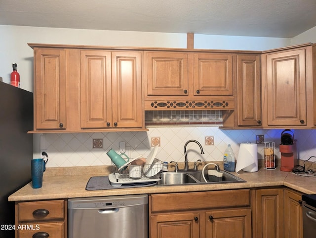 kitchen with dishwasher, decorative backsplash, black refrigerator, and sink