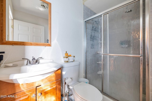 bathroom with vanity, a shower with shower door, and toilet