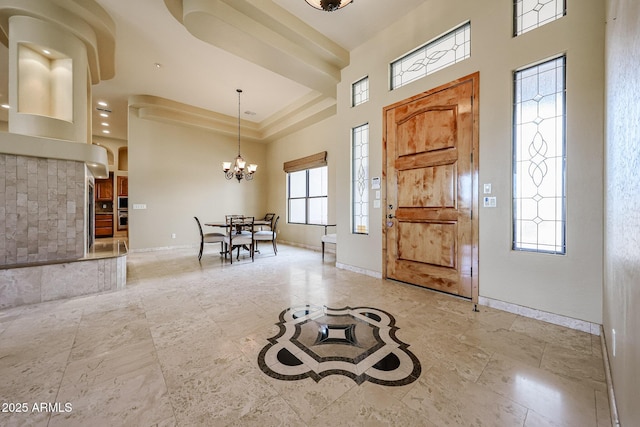 foyer entrance featuring a notable chandelier, a tray ceiling, and a high ceiling