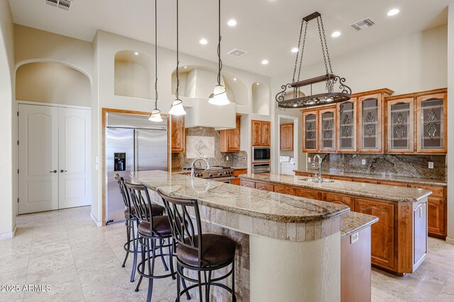 kitchen featuring sink, hanging light fixtures, a high ceiling, built in appliances, and a spacious island