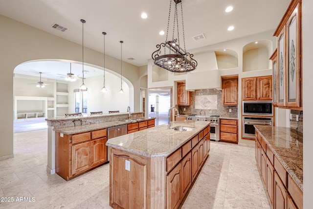 kitchen featuring a spacious island, sink, built in appliances, pendant lighting, and backsplash