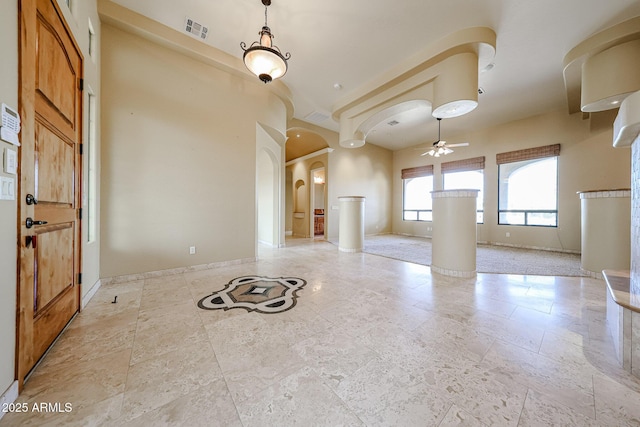 unfurnished living room featuring ceiling fan and decorative columns