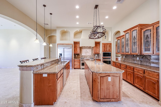 kitchen with hanging light fixtures, built in appliances, and a spacious island