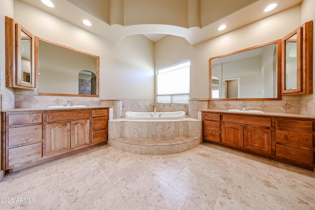 bathroom featuring vanity, a relaxing tiled tub, and backsplash