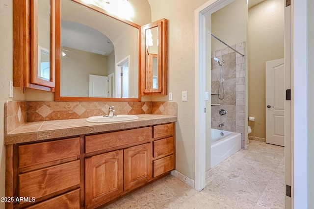 full bathroom with tasteful backsplash, tiled shower / bath, vanity, and toilet