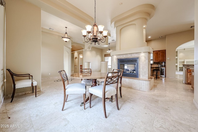 dining room with a tile fireplace and a notable chandelier