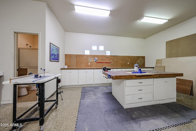 kitchen with white cabinetry, a center island, and butcher block counters