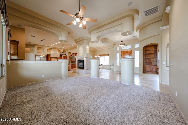 unfurnished living room featuring light carpet, built in shelves, a tile fireplace, and ceiling fan