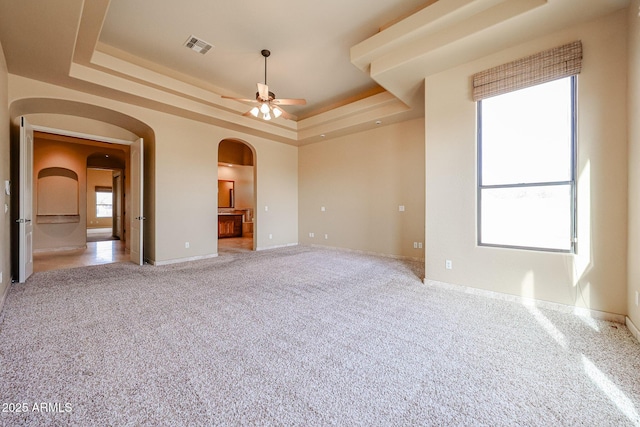 carpeted spare room with ceiling fan and a tray ceiling