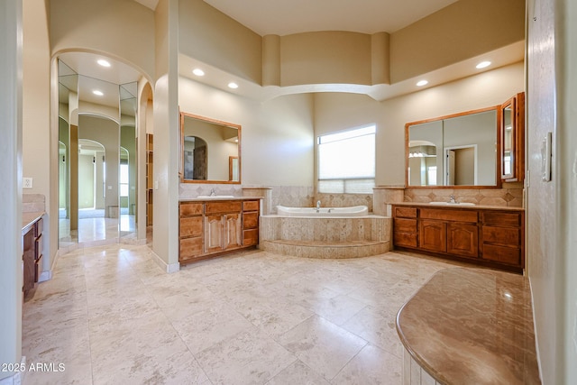 bathroom with vanity, a high ceiling, and tiled tub