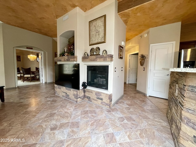 living area with arched walkways, a glass covered fireplace, and baseboards