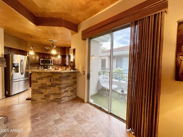 kitchen with appliances with stainless steel finishes, a peninsula, and pendant lighting