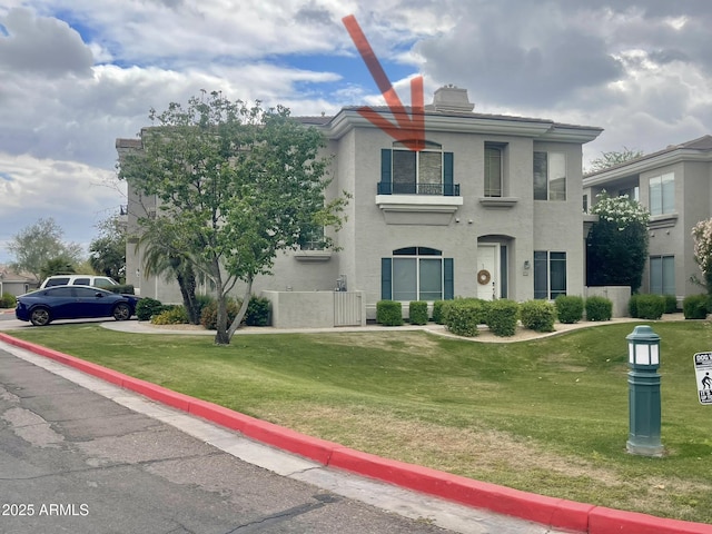 view of front of property featuring a chimney, a front yard, and stucco siding