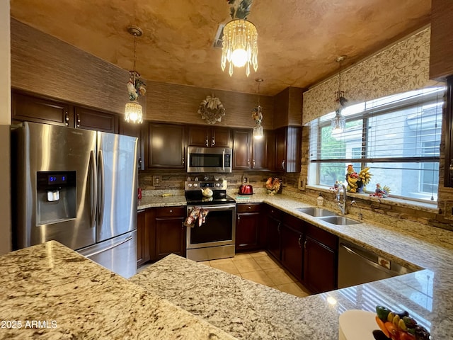 kitchen featuring appliances with stainless steel finishes, a sink, light tile patterned floors, tasteful backsplash, and light stone countertops