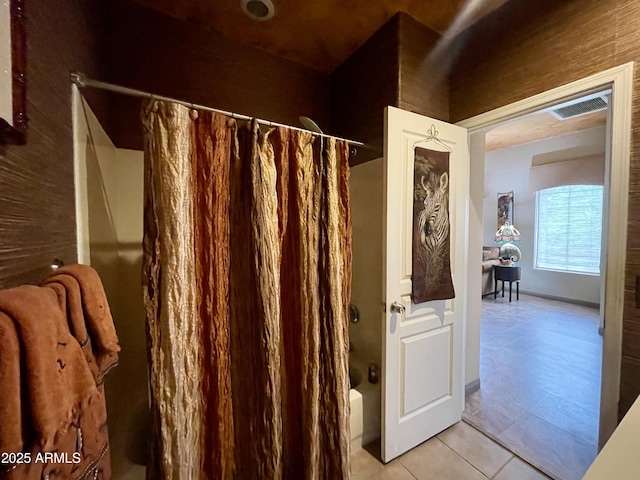 full bath featuring shower / tub combo and tile patterned flooring