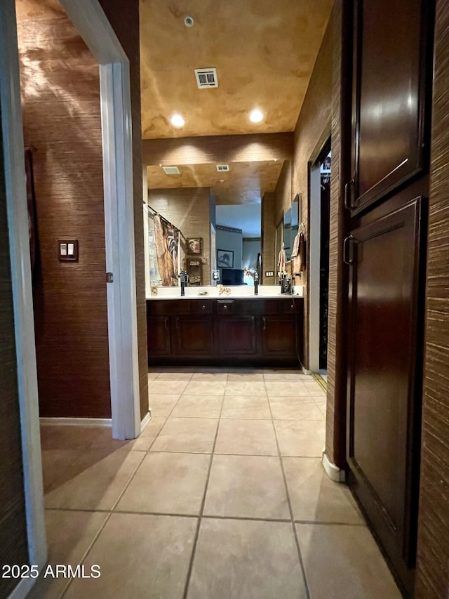 bathroom featuring tile patterned floors, double vanity, baseboards, a shower, and recessed lighting