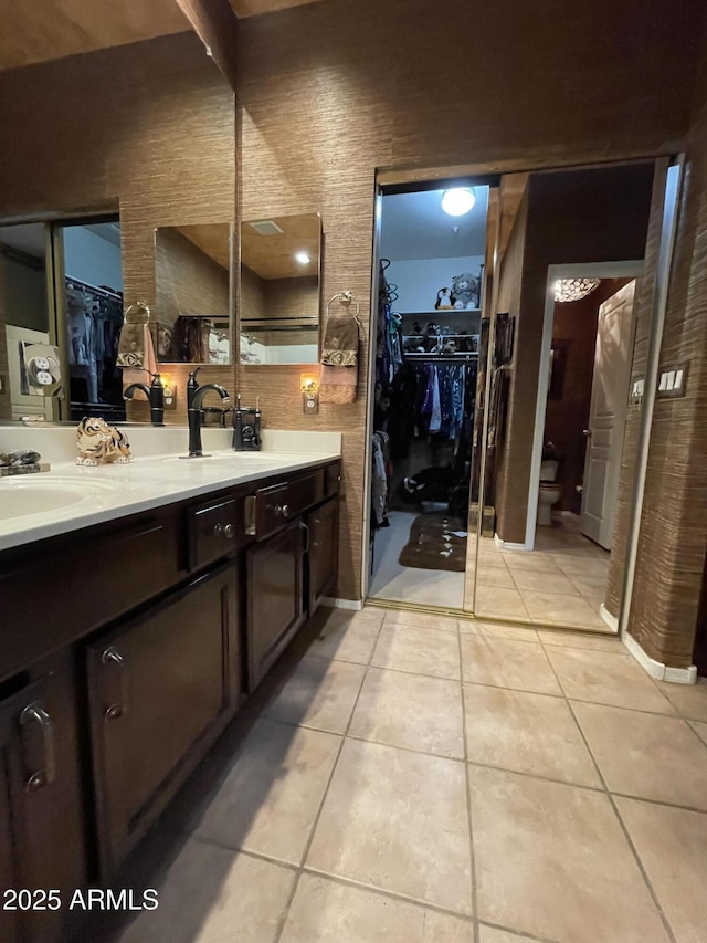 full bath featuring tile patterned flooring, double vanity, toilet, and a spacious closet