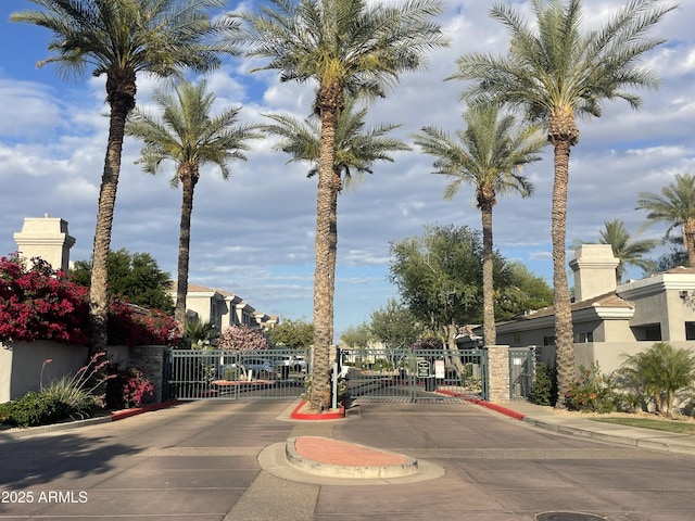 view of street featuring a gate, a gated entry, and curbs