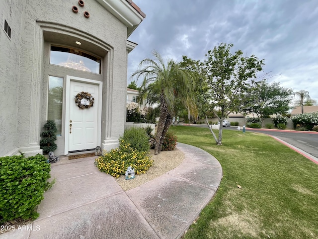 doorway to property with a lawn and stucco siding