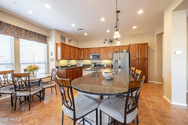 13050 W Pinnacle Vista Dr, Peoria, AZ 85383 - kitchen featuring a breakfast bar, hanging light fixtures, dark stone countertops, stainless steel appliances, and a kitchen island with sink