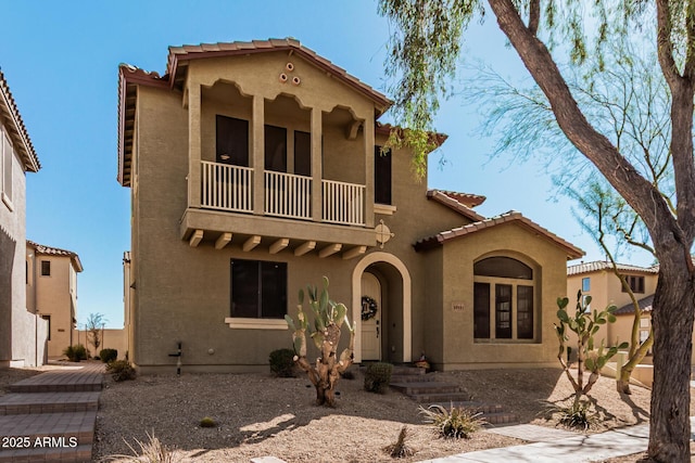 mediterranean / spanish-style house with a tiled roof, a balcony, and stucco siding