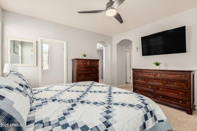 bedroom featuring a ceiling fan, arched walkways, and light carpet