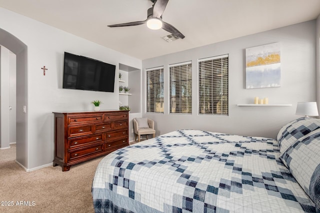 bedroom with light carpet, visible vents, arched walkways, a ceiling fan, and baseboards