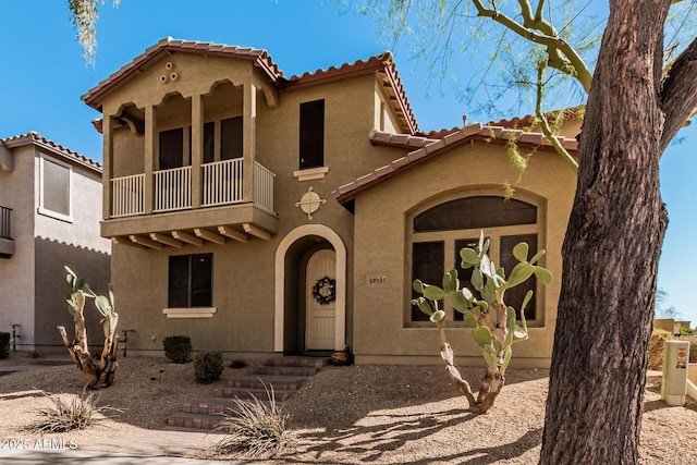 mediterranean / spanish house with a tiled roof, a balcony, and stucco siding