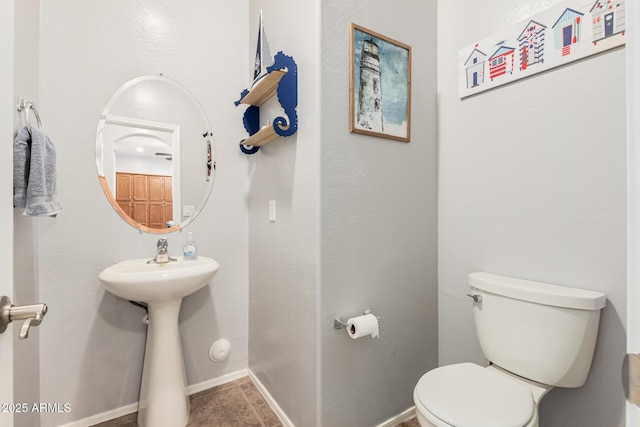 bathroom with a sink, toilet, and baseboards