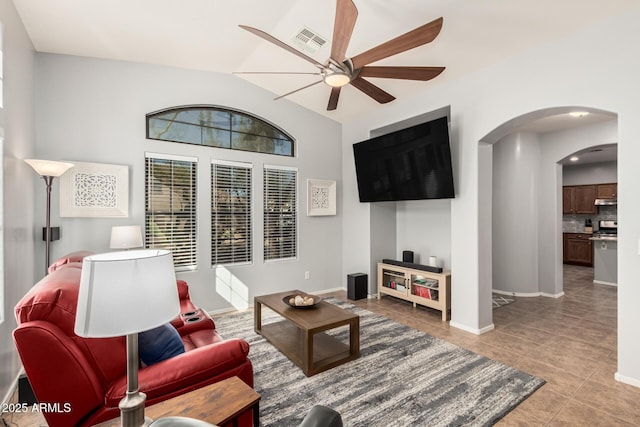 tiled living room with baseboards, visible vents, arched walkways, a ceiling fan, and lofted ceiling