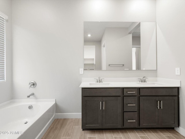 17621 W Pierson St, Goodyear, AZ 85395 - bathroom with wood tiled floors, double vanity, a bath, baseboards, and recessed lighting
