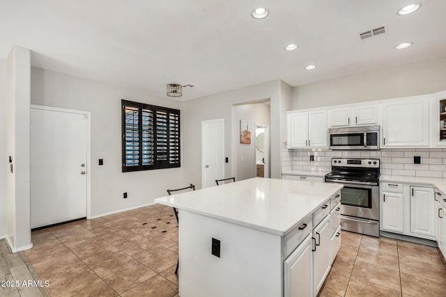 9350 W Williams St, Tolleson, AZ 85353 - kitchen with appliances with stainless steel finishes, a kitchen island, backsplash, light countertops, and white cabinetry