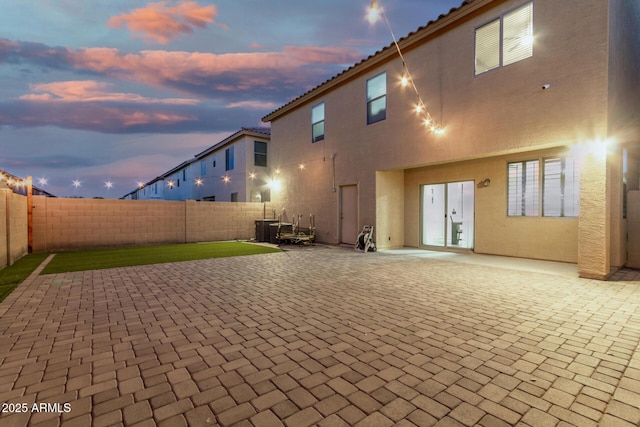 9350 W Williams St, Tolleson, AZ 85353 - back of house at dusk with stucco siding, a patio, and a fenced backyard