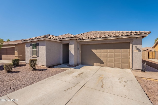 view of front of property featuring a garage, driveway, a tile roof, and stucco siding