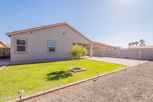 rear view of property with a patio area, a fenced backyard, a yard, and stucco siding