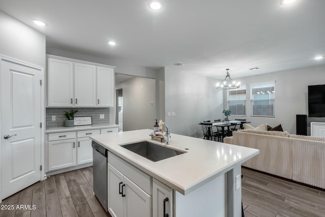 kitchen featuring dishwasher, white cabinets, sink, hanging light fixtures, and a notable chandelier