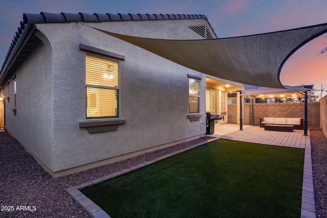 back house at dusk featuring a patio area