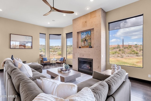 living room featuring baseboards, recessed lighting, a glass covered fireplace, a ceiling fan, and wood-type flooring