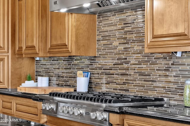 kitchen featuring dark stone countertops, backsplash, stainless steel gas stovetop, and wall chimney range hood