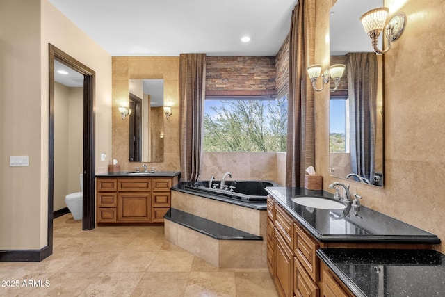 bathroom with two vanities, a garden tub, toilet, and a sink