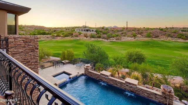 pool at dusk with a patio area, a lawn, and a pool with connected hot tub